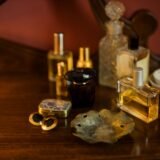 Flacoane de parfum din sticlă așezate pe o măsuță de toaletă, în lumina caldă a dimineții