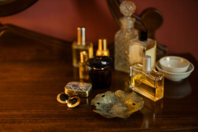 Flacoane de parfum din sticlă așezate pe o măsuță de toaletă, în lumina caldă a dimineții