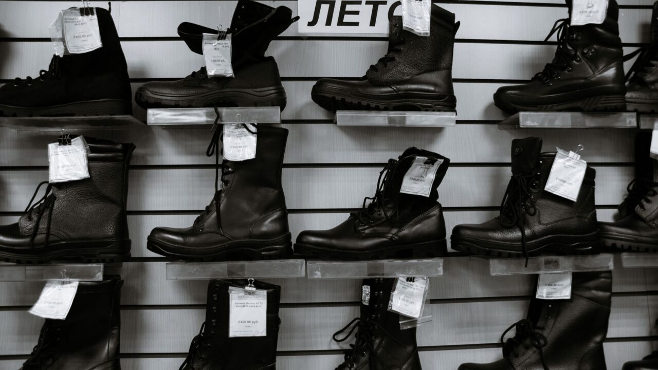 Rând de pantofi, mocasini, botine și sneakersi din piele, așezați ordonat pe o podea de lemn