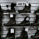 Rând de pantofi, mocasini, botine și sneakersi din piele, așezați ordonat pe o podea de lemn