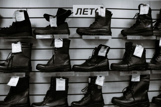 Rând de pantofi, mocasini, botine și sneakersi din piele, așezați ordonat pe o podea de lemn