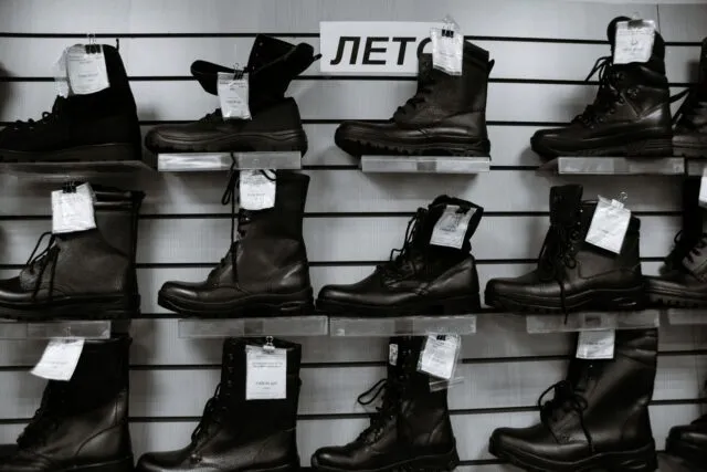 Rând de pantofi, mocasini, botine și sneakersi din piele, așezați ordonat pe o podea de lemn