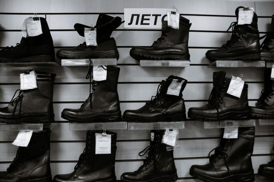 Rând de pantofi, mocasini, botine și sneakersi din piele, așezați ordonat pe o podea de lemn